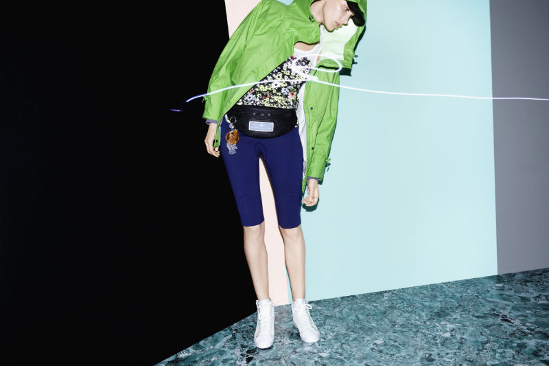 Девушка в синих шортах-лосинах и зеленой куртке-ветровке adidas by Stella McCartney